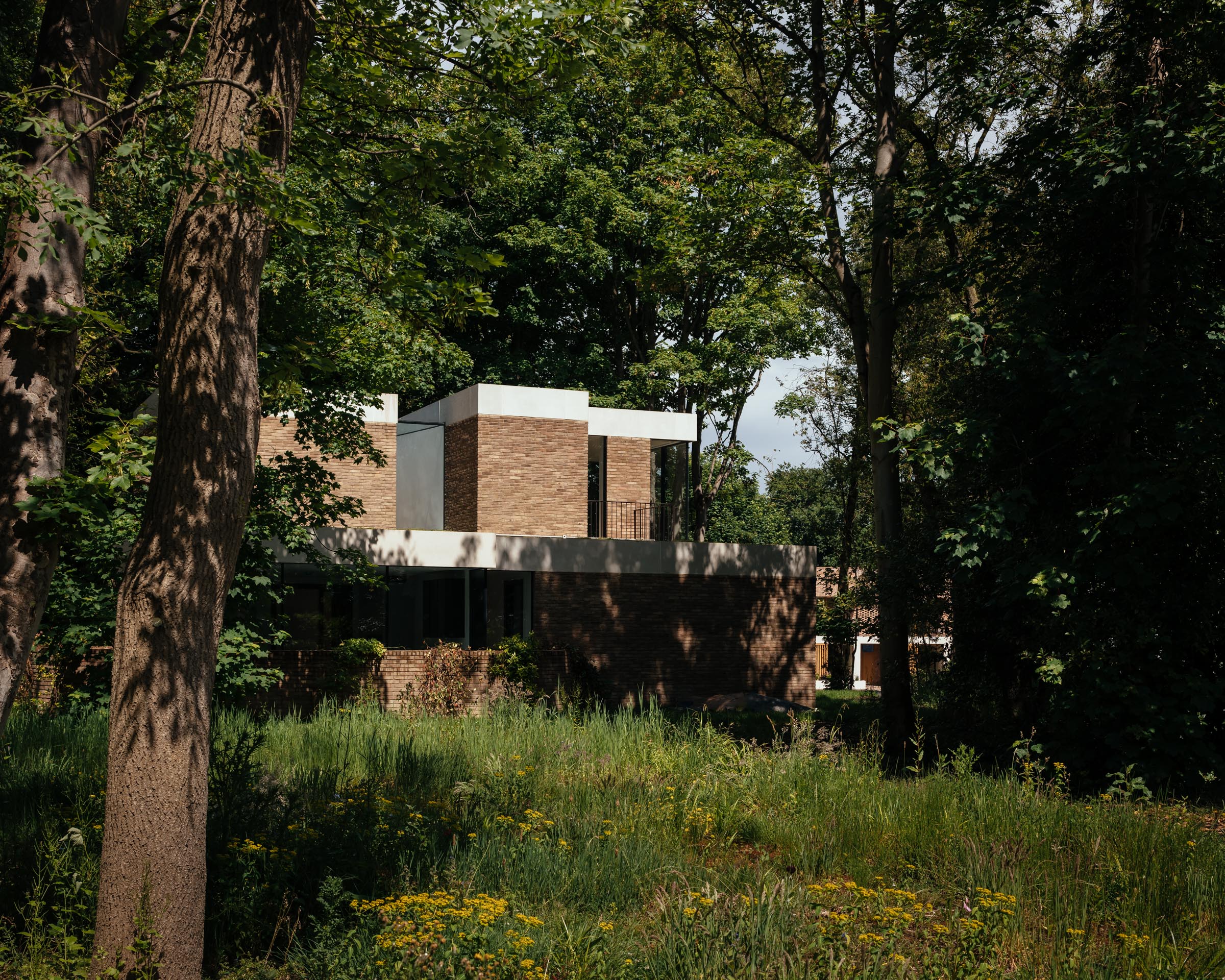 Various artisanal facing bricks connect homes in a revalued wooded English estate